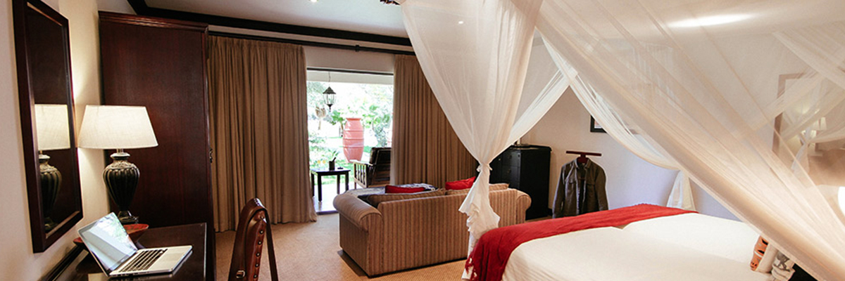 A luxury hotel room including a large bed and sofa with doors out onto the plains