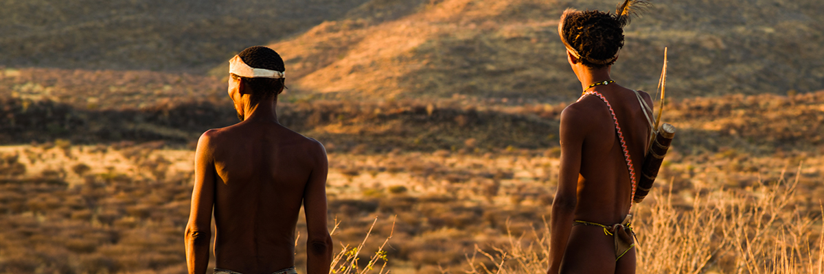 Two San Bushmen overlook the desert plains at sunset.